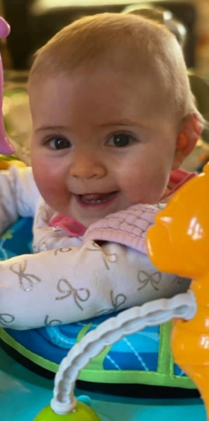 Baby Brynn in a baby walker smiling at camera